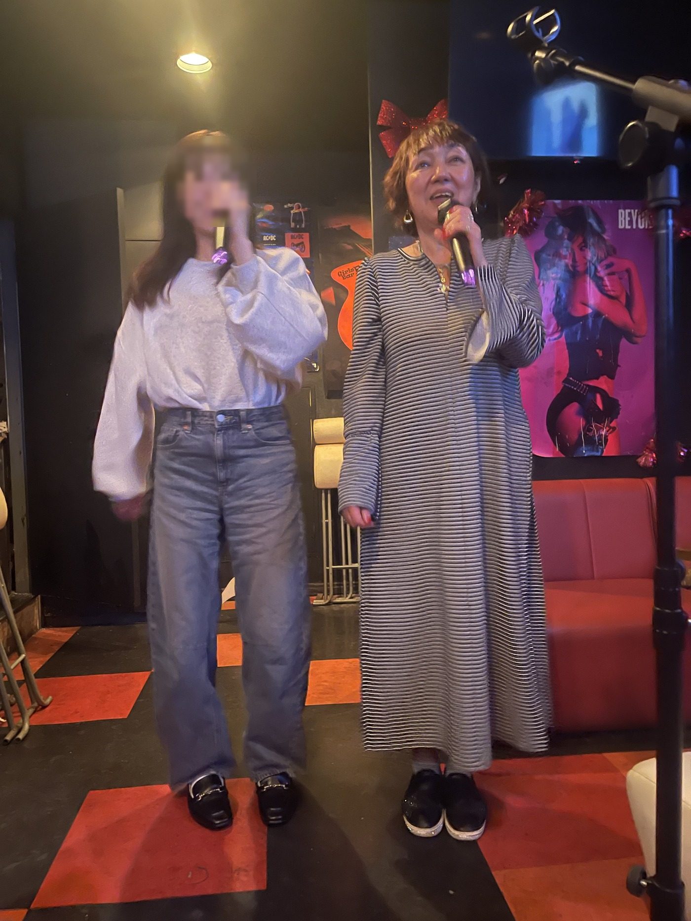 赤いリボンをつけたママが、お客さんと並んでデュエットしている様子