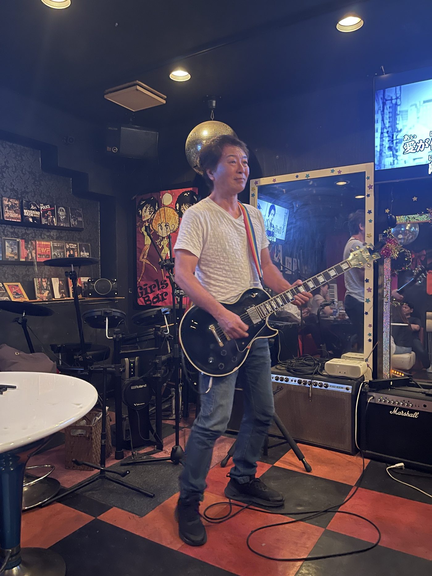 レスポールを構えるマスター。店内には電子ドラムやアンプが並ぶ
